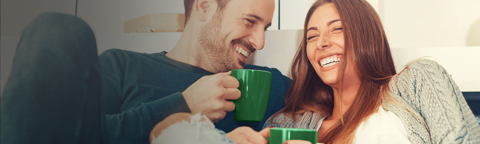 couple on couch laughing with coffee cups
