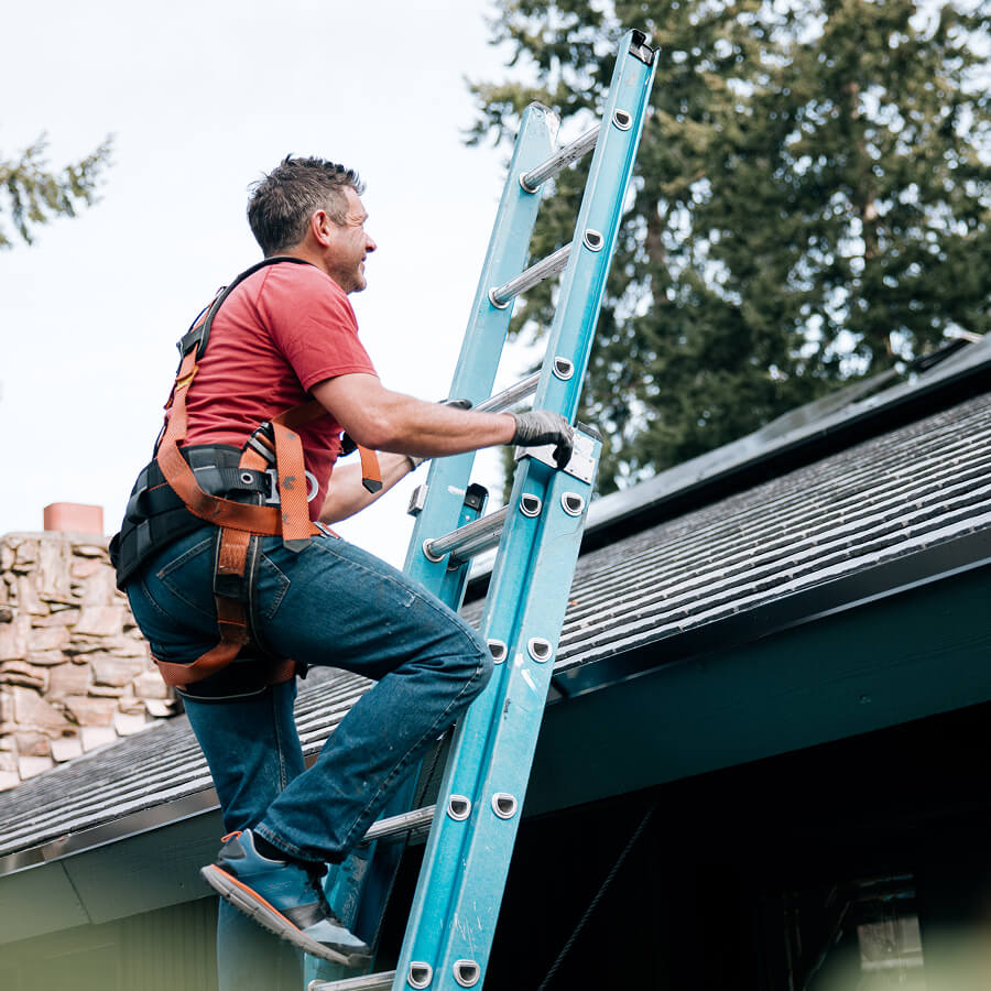 Man climbing ladder to work on roof